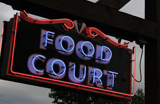 Vintage Purple Neon Food Court Sign Outdoors With Trees in Background