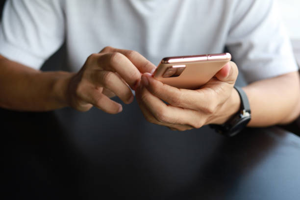 istock Cropped image of an Asian man is sitting at a table, using his smartphone to text 1494851215