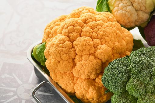 Colorfu cauliflower. Various sort of cauliflower on stone tiles gray concrete background. Purple, yellow, white and green color cabbages. Broccoli and Romanesco. Agricultural harvest. Mock up.