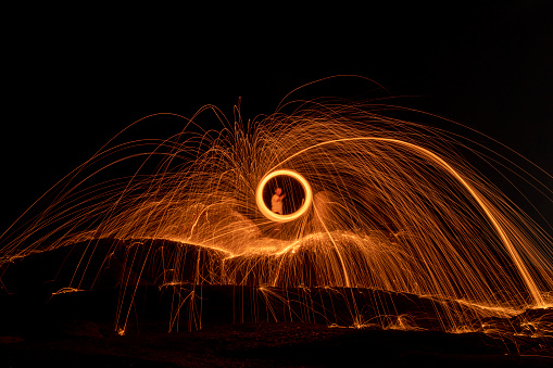 Lighting from spinning steel wool on stone near the sea of Steel Wool Photography.