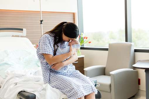 While sitting in the hospital room, the single mother admires her newborn baby.