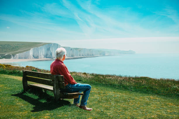 istock Senior man sitting alone on bench looking at sea view 1494853160