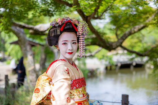 Portrait of Japanese Maiko (Geisha in training) standing in public park in Gion, Kyoto