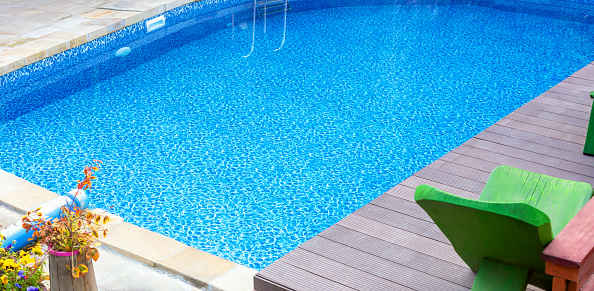 Clear blue swimming pool in yard. Rest and relaxation