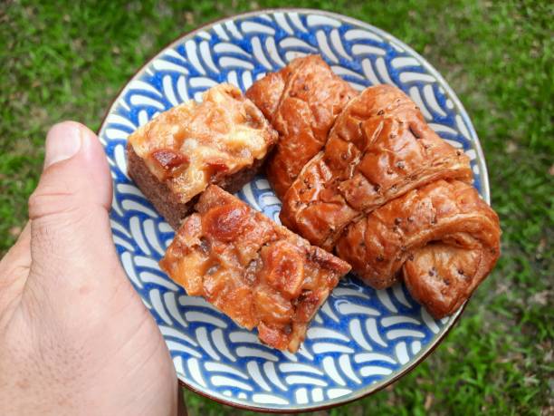 Hand holding Croissant and Toffee Cake on plate.