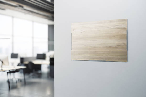 istock Blank wooden printed poster with place for your logo or text on light grey wall background in modern office area with blurred furniture on background. 3D rendering, mockup 1494865931