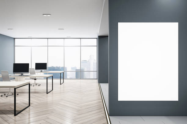 istock Front view on blank white poster on dark grey wall with space for your logo advertising in modern open space office with table and chairs on wooden floor. 3D rendering, mockup 1494866524