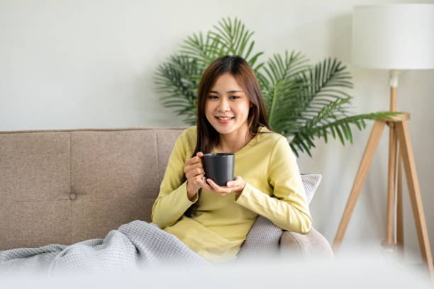 istock Young asian woman is drinking coffee and lying on the big comfor 1494867366