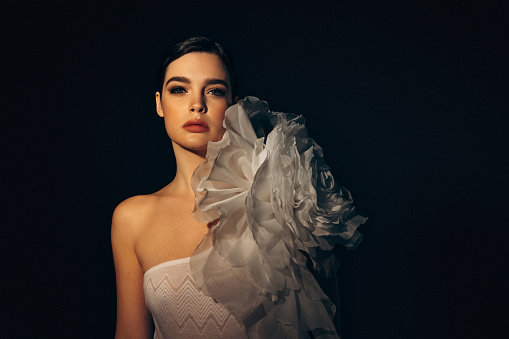Studio shot of young beautiful woman wearing amazing dress with flower