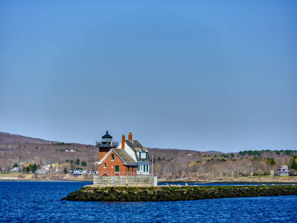 morning light on the rockland breakwater lighthouse and jetty in rockland maine as seen from the vinalhaven ferry heading out into open water with the town of rockland maine in the background - rockland breakwater light imagens e fotografias de stock