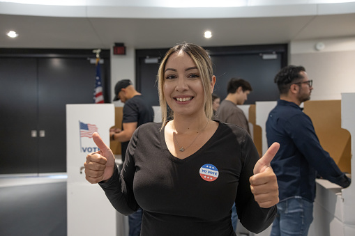 Voting in a presidential election. Holding a voting sticker in Spanish.