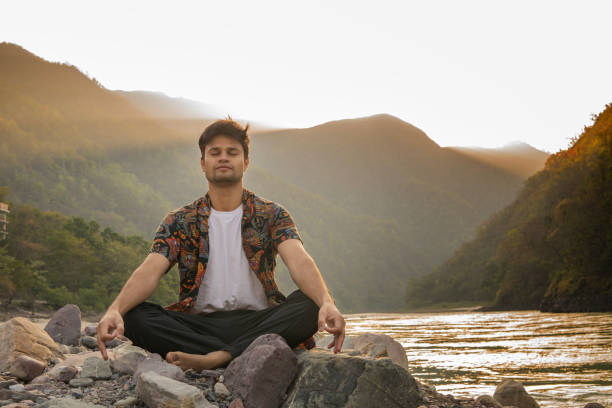 istock Young man meditating on rocks at lakeshore during vacation 1494874471