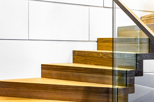 detail of hardened glass balustrade in house with wooden stairs