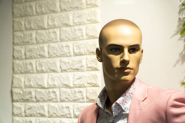 Portrait of a male mannequin, dressed in an elegant and summery suit, posing behind a store window