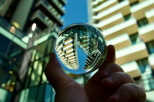 Hand holding crystal ball against modern buildings