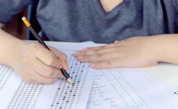 istock Students hand holding pencil writing selected choice on answer sheets and Mathematics question sheets. students testing doing examination. school exam 1494879669