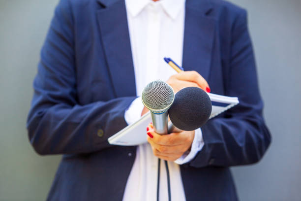 istock News reporter at media event or press conference, holding microphone, writing notes. Broadcast journalism concept. 1494885418
