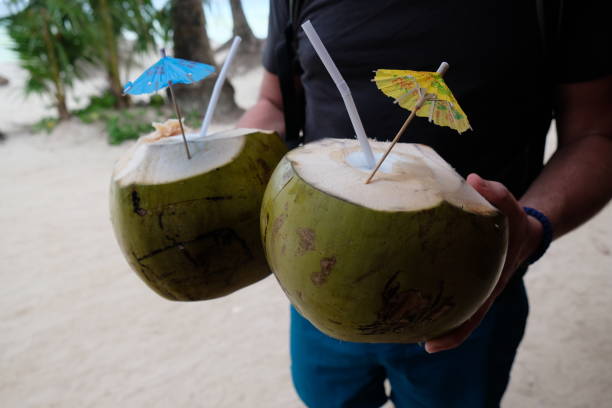 istock coconuts with straws and umbrellas in male hands 1494888780