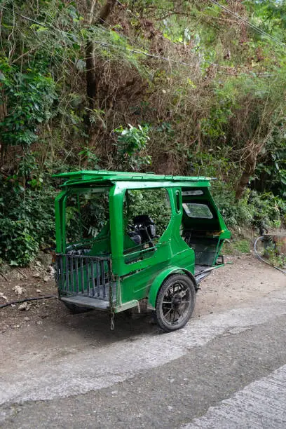 Photo of green tuk tuk parked in the jungle