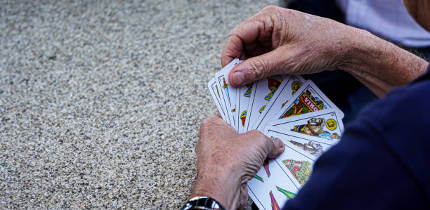 senior und rentner spielen mit einem spanischen kartenspiel auf einem granitsteintisch in einem ländlichen bergdorf - table house of cards strategy business stock-fotos und bilder