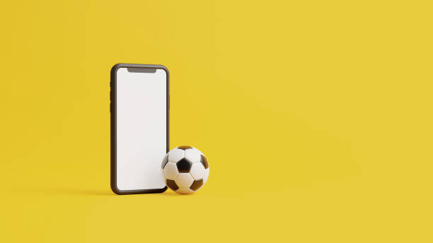 istock Mobile phone with a white screen and a soccer ball on a yellow background with copy space 1494894511