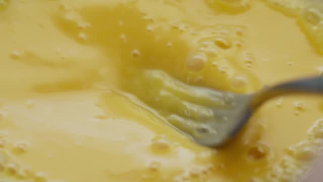 Eggs being whisked in a bowl using a fork