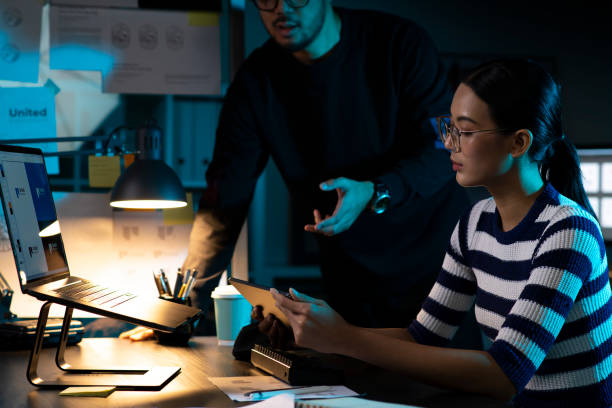 istock Two Asian Graphic designers are discussing and working in the office at night. 1494899026