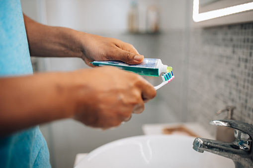 Embracing a daily dental care routine, a mid adult African American man focuses on the meticulous task of brushing his teeth in the bathroom