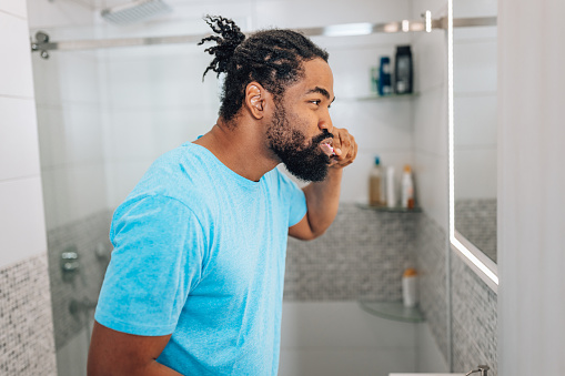 With a determination to achieve a thorough teeth cleaning, a mid adult African American man devotes time to his oral care routine
