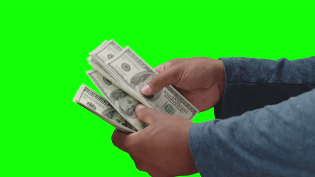 Hands of man counting 100 dollars banknotes on green background