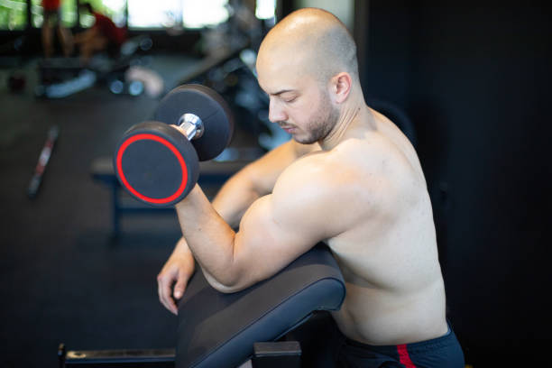 Young man training in gym with dumbbells