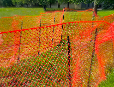 special effects close up of a red plastic safety fence, set up surrounding a ditch at a building renovation site, Long Island, New York