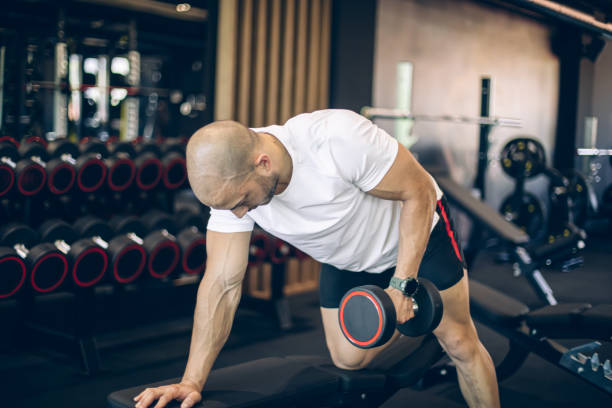 istock Young man training in gym with dumbbells 1494903271