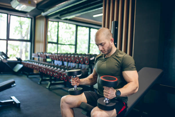 istock Young man training in gym with dumbbells 1494903666