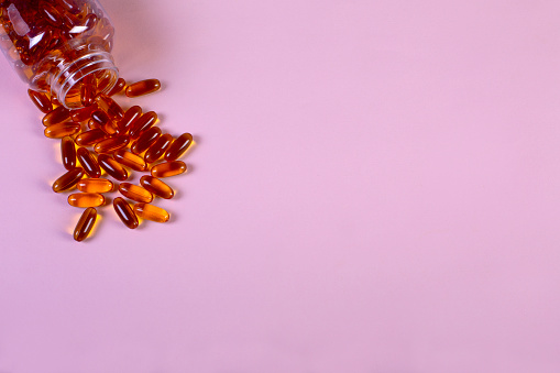 Omega 3 Fish Oil Capsules Spilling Out Of A Bottle On A Pink Background.