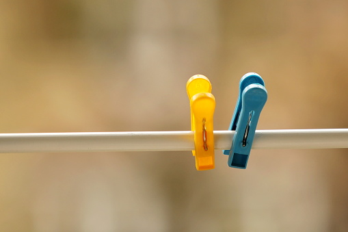 Two blue and yellow clothespins on a rope. Symbol of the Ukrainian and Swedish flags. Laundry and house cleaning. Household items for the organization of everyday life. Plastic products in everyday