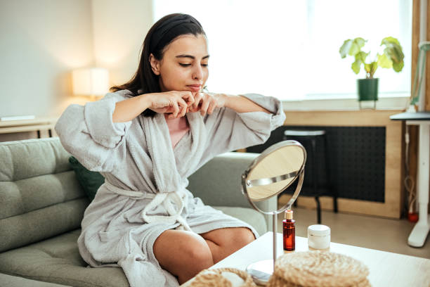 Feeling younger Woman sits on a sofa in the living room and massages her face facial massage stock pictures, royalty-free photos & images