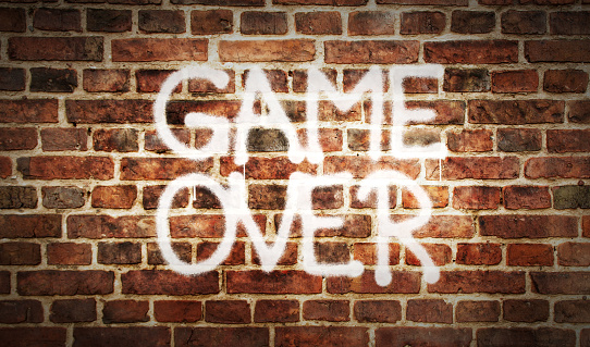 Game over sign spray painted on the brick wall. Graffiti art concept retro game console play end symbol. Urban abstract artwork. Airbrush paint with template in hand illustration.