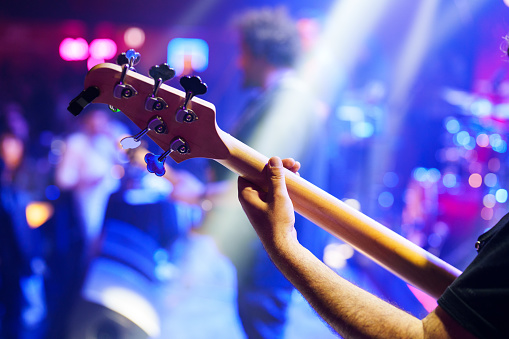 Males playing guitar or drum and female singing on a stage at night on weekend, Live music concept.