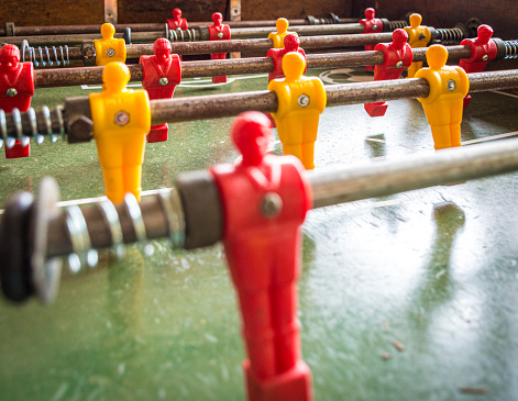 foosball tablebones in the foosball background with blur on the front and focused on the back with red and yellow table football dolls