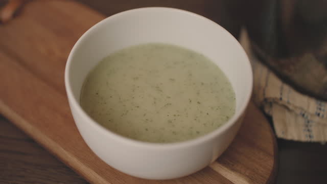 pouring vegan leek potato soup in a bowl