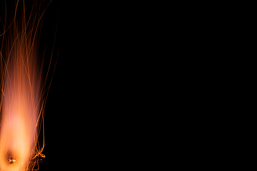 Close-up of three sparklers shaped as 'NUMBER 100' emitting sparks while burning against black background.