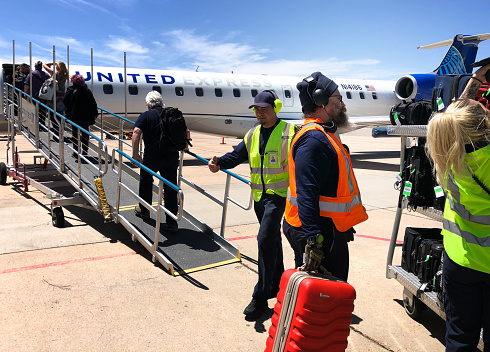 Santa Fe, NM: As passengers board, ground crew gate check luggage for a United Airlines commuter jet at the Santa Fe airport.