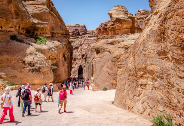 turistas que entran en el siq, que conduce al tesoro y la antigua ciudad de petra, jordania. - petra antiquities jordan middle east fotografías e imágenes de stock