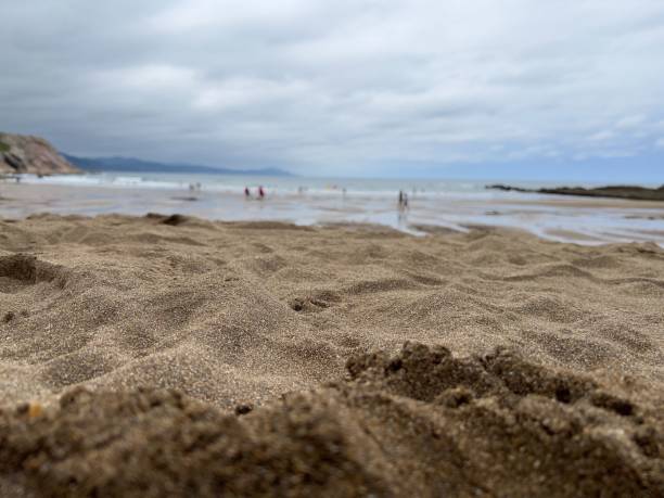 an empty beach with a few people walking in the distance