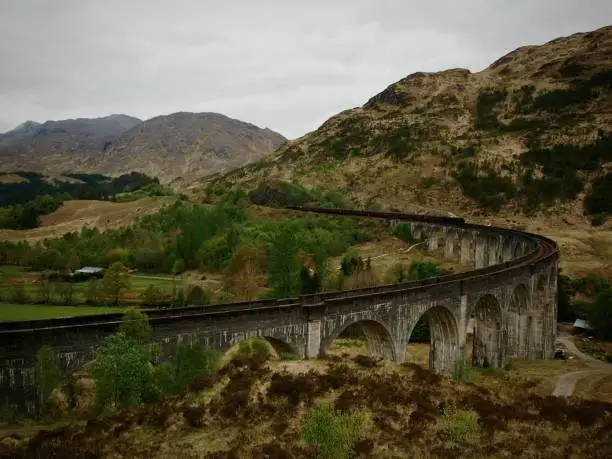 Steam train crossing arched viaduct through the Scottish Highlands