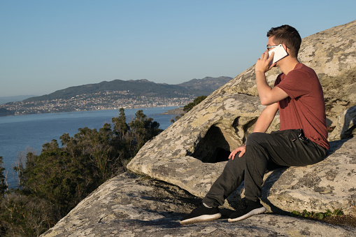 Man sitting on a rock talking on mobile phone