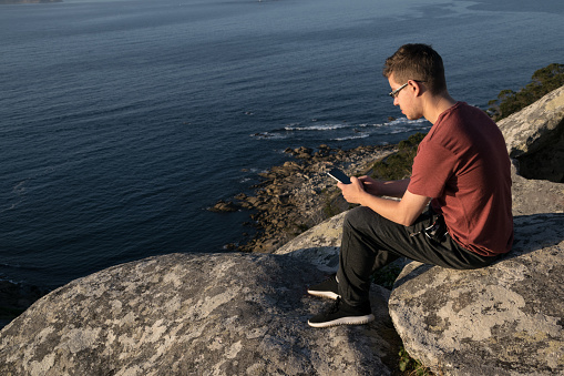 Man on the edge of a cliff using mobile phone