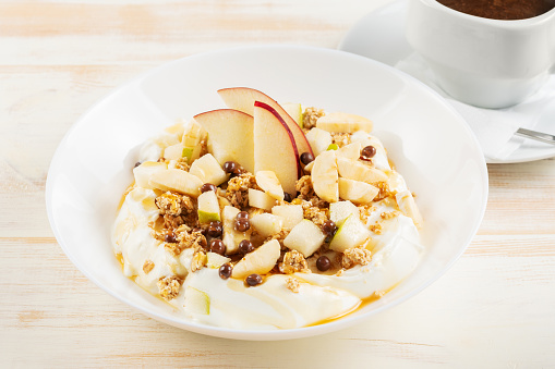 Healthy Îreakfast concept. Yogurt with flakes, fruits and honey on wooden background.