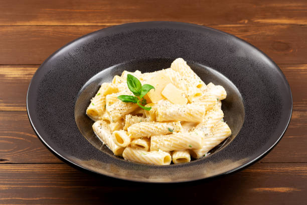 istock Rigatoni with cream sauce, parmesan cheese and basil on black plate. 1494924806